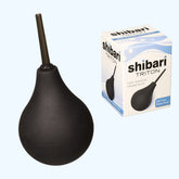 Image of a black Triton Easy Squeeze Enema Bulb by Shibari with a long flexible tip next to its packaging box. The white box, accented in blue, is labeled "shibari TRITON Easy Squeeze Enema Bulb" and showcases features such as "BPA Free," "Water-Proof," and made from Non-Toxic Medical-Grade PVC.